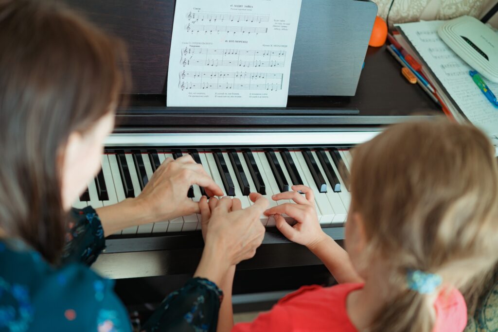 a woman and a little girl playing a piano